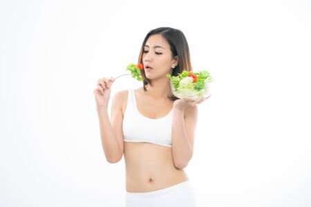 Beautiful asian young woman healthy food in white sport bra eating salads with healthy food on a white background.の写真素材