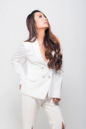 High fashion shot of beautiful portrait young woman smiling long brown hair wearing white suit show their chest at studio shoot isolated on white background.の写真素材