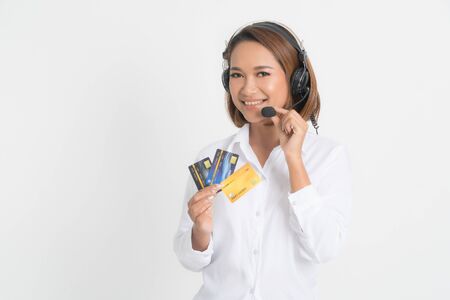 Friendly female helpline operator or call center showing blank credit card, headset holding her arms crossed isolated on white background.の写真素材