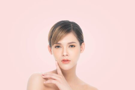 Beauty young woman with clean fresh skin, Proposing a product. Gestures for advertisement isolated on pink background, at copy space.の写真素材