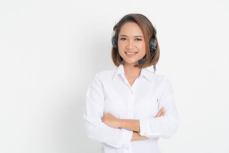 Call center operator woman short hair, wearing a white shirt with headset standing crossing her arms isolated on white background.の写真素材
