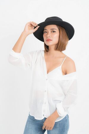 Beautiful portrait asian woman brown short bob wearing black hat, white shirt and blue jeans in stand position with fashion on isolated white background.の写真素材
