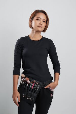 Young woman makeup artist with brushes and makeup tools on grey background.の写真素材