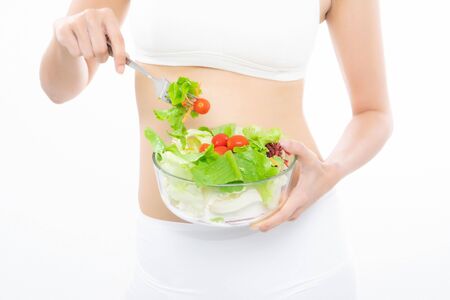 Beautiful asian young woman healthy food in white sport bra eating salads with healthy food on a white background.の写真素材