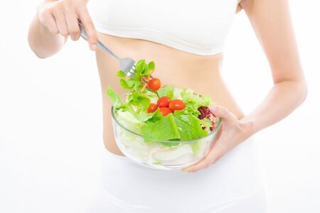 Beautiful asian young woman healthy food in white sport bra eating salads with healthy food on a white background.の写真素材