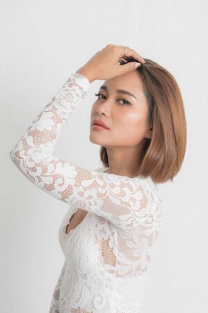 Beautiful portrait asian woman brown short bob wearing a white lace bodysuit on isolated white background. In close-up viewの写真素材