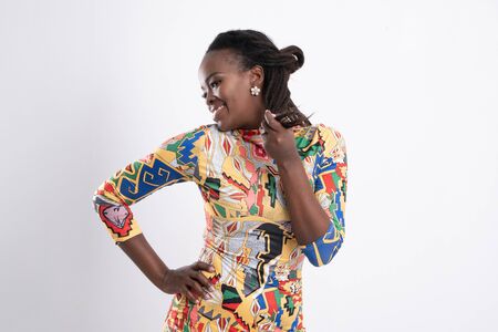 Beautiful African woman hair dreadlocks with a happy posture wearing a flower-patterned dress, wearing black high-heeled shoes, wearing earrings full length body portrait isolated on white background.の写真素材
