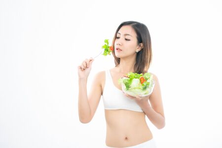 Beautiful asian young woman healthy food wearing white underwear eating salads with healthy food isolated on a white background.の写真素材