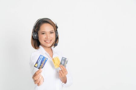 Friendly female helpline operator or call center showing blank credit card, headset holding her arms crossed isolated on white background.の写真素材