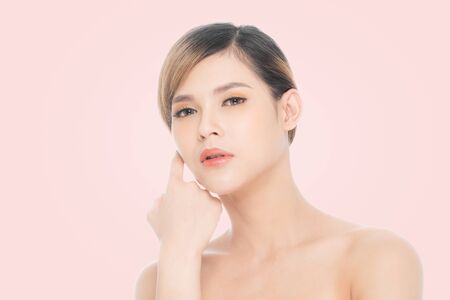 Beauty young woman with clean fresh skin, Proposing a product. Gestures for advertisement isolated on pink background, at copy space.の写真素材