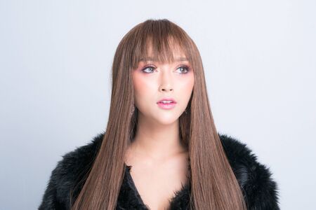 Beautiful asian model posing in a fur coat is fashion photography at studio lighting shoot isolated on gray background.の写真素材