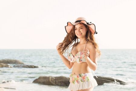 Portrait of smiling beautiful young woman wearing summer hat with large brim at beach.の写真素材