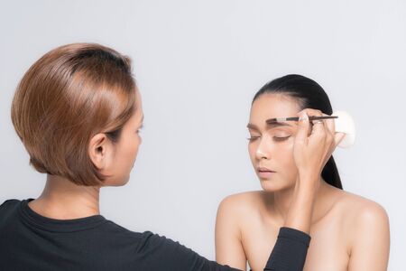 Young beautiful asian woman applying makeup by makeup artist on location.の写真素材