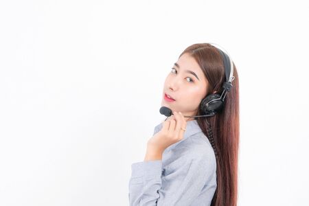 Portrait of happy smiling female customer support phone operator short hair, wearing a gray shirt with headset standing one side holding the earphone isolated on white background.の写真素材