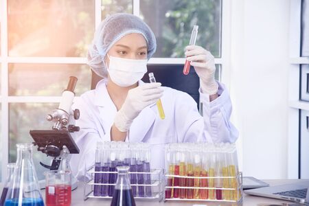 Woman scientist wearing white glue and a hair cap working with laptop, experiment at laboratory.の写真素材