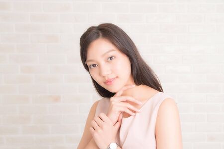Close up, Beautiful asian pretty woman long brown hair smiling and facing her side view with wearing a black t-shirt and jeans standing positng on beige color wall.の写真素材