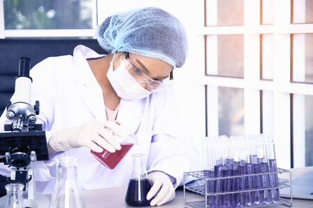 Woman scientist wearing white glue and a hair cap working with laptop, experiment at laboratory.の写真素材