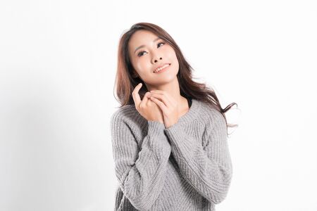 Pretty smiling joyfully being happy asian woman portrait with perfect skin and wearing a gray sweater in profile at studio shot isolated on white background.の写真素材