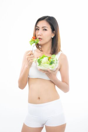 Beautiful asian young woman healthy food in white sport bra eating salads with healthy food on a white background.の写真素材