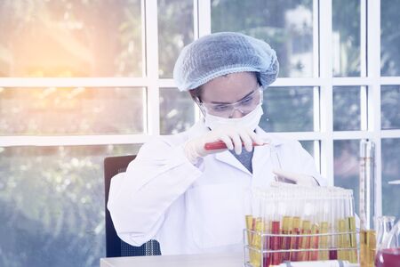 Woman scientist wearing white glue and a hair cap working with laptop, experiment at laboratory.の写真素材