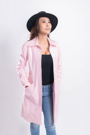 Young elegant woman in trendy pink coat wearing a black hat, at fashion studio portrait shot isolated on white background.の写真素材