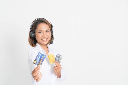 Friendly female helpline operator or call center showing blank credit card, headset holding her arms crossed isolated on white background.の写真素材