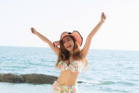 Portrait beautiful young woman wearing summer hat with brim, She is smiling and happiness jumping on the beach.の写真素材
