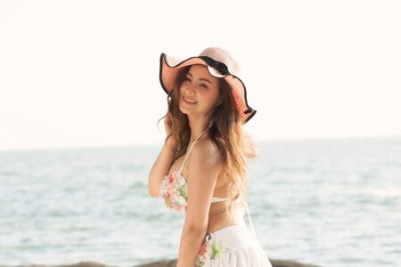 Portrait of smiling beautiful young woman wearing summer hat with large brim at beach.の写真素材