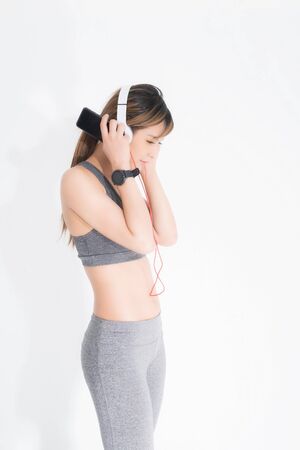 Fitness woman listening to music wearing white music headphones, enjoys sports and healthy lifestyle isolated on a white background. She is relaxing and happiness.の写真素材
