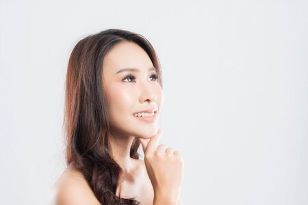 Beautiful young woman with clean fresh skin, Hair sleek, Proposing a product. Gestures for advertisement on gray background, Front view, with copy space.の写真素材