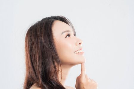 Beautiful young woman with clean fresh skin, Hair sleek, Proposing a product. Gestures for advertisement on gray background, Front view, with copy space.の写真素材