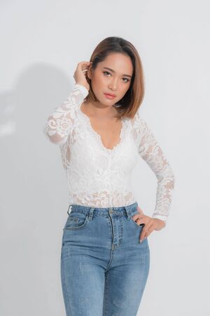 Beautiful portrait asian woman brown short bob wearing a white lace bodysuit and blue jeans in stand position with fashion on isolated white background.の写真素材
