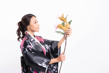 Beautiful attractive asian woman wearing traditional japanese kimono with a bouquet of beautiful flowers isolated on white backgroundの写真素材