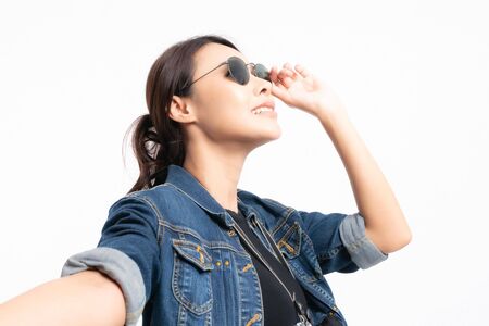 Portrait of happy asian woman in a denim jacket wearing sunglasses holding hand of her boyfriend at studio shot concept isolated on white background. Couple enjoying travel.の写真素材