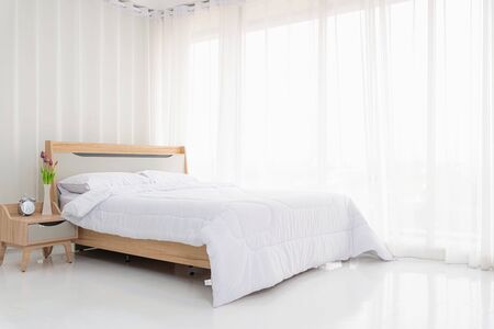 Interior white bedroom with white curtains and white pillows on wooden bed elegant classic for rest and sleep. Modern white bedroom bright.の写真素材
