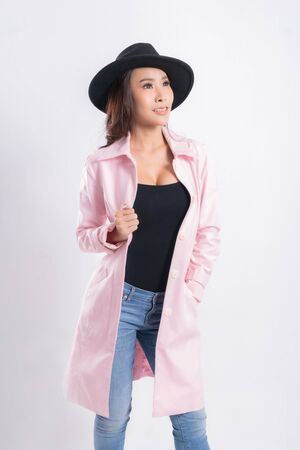 Young elegant woman in trendy pink coat wearing a black hat, at fashion studio portrait shot isolated on white background.の写真素材