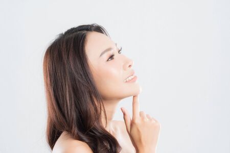 Beautiful young woman with clean fresh skin, Hair sleek, Proposing a product. Gestures for advertisement on gray background, Front view, with copy space.の写真素材