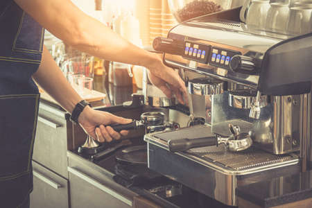 Close up, Barista making an espresso with a classic Italian coffee machine with steam and sunlight in background.の写真素材
