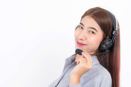 Portrait of happy smiling female customer support phone operator short hair, wearing a white shirt with headset standing one side holding the earphone isolated on white background.の写真素材