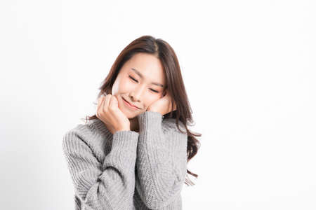 Pretty smiling joyfully being happy asian woman portrait with perfect skin and wearing a gray sweater in profile at studio shot isolated on white background.の写真素材