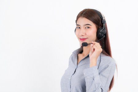 Portrait of happy smiling female customer support phone operator short hair, wearing a white shirt with headset standing one side holding the earphone isolated on white background.の写真素材
