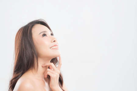 Beautiful young woman with clean fresh skin, Hair sleek, Proposing a product. Gestures for advertisement on gray background, Front view, with copy space.の写真素材