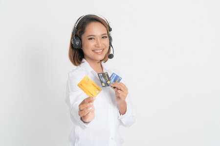 Friendly female helpline operator or call center showing blank credit card, headset holding her arms crossed isolated on white background.の写真素材