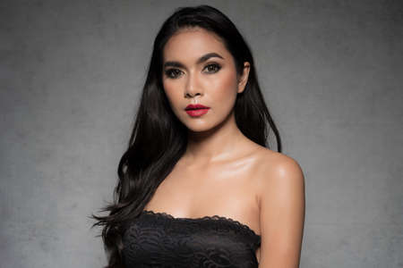 Sexy slim woman wearing black bra fashionable is sexy dark tone fashion posing studio shot isolated on gray background.の写真素材