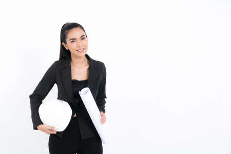 Portrait young engineer woman wearing black suit holding blueprint and white safety-helmet in shot studio isolated on white background.の写真素材