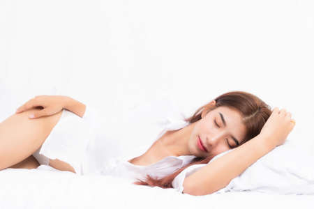 Beautiful young pretty asian woman wake up and stretching with white shirt at the white bed in the morning.の写真素材