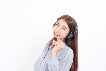 Portrait of happy smiling female customer support phone operator short hair, wearing a white shirt with headset standing one side holding the earphone isolated on white background.の写真素材