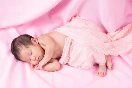 Portrait of a one month old sleeping, newborn baby girl on a pink blanket. Concept portrait studio fashion newborn.の写真素材