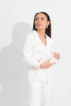 Fashion style catalog clothing for business woman black long hair natural make up wear white suit costume perfect body shape suit, carrying white bag at studio shoot on white background and shadow.の写真素材