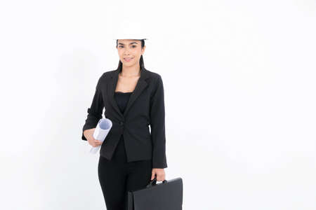 Portrait young engineer woman wearing black suit and white safety-helmet holding blueprint and bag in shot studio isolated on white background.の写真素材